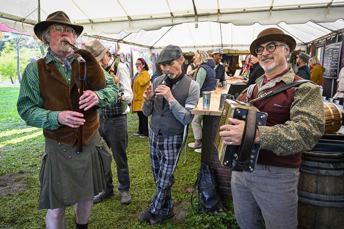 Musician leaning against a rock wall playing guitar